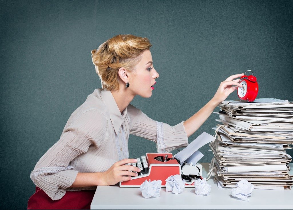 woman using typewriter beside stacks of paper