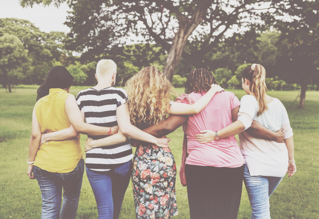 Women holding each other and walking away in a park