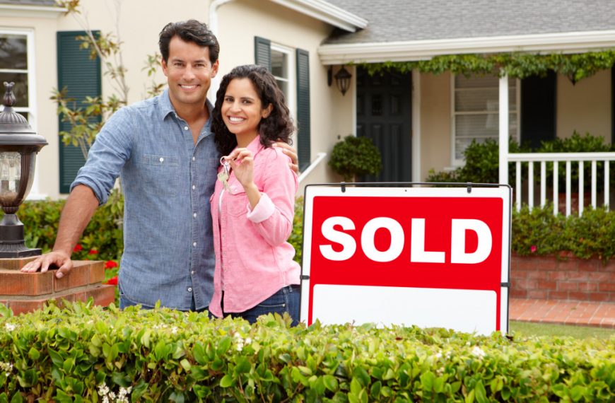buying home with couple beside sold sign