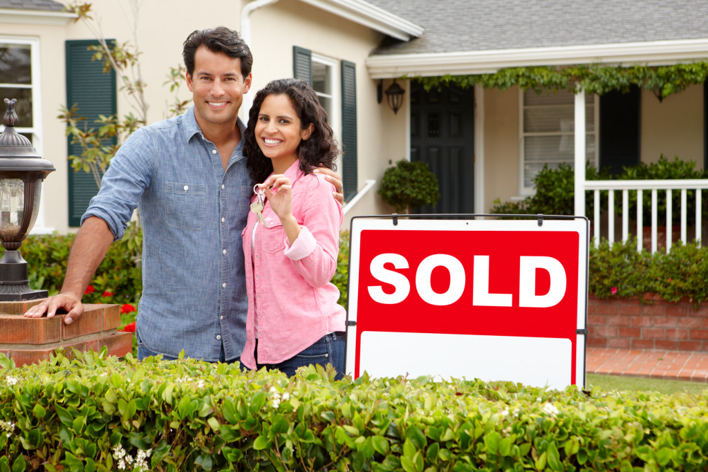 buying home with couple beside sold sign